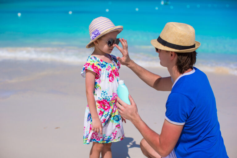 Parent applying sunscreen on child at the beach